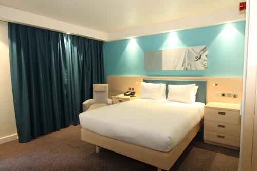 a bedroom with a white bed and a blue wall at Hampton By Hilton London Docklands in London