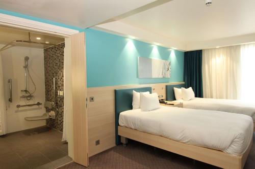 ロンドンにあるハンプトン バイ ヒルトン ロンドン ドックランズのベッド2台とバスルームが備わるホテルルームです。
