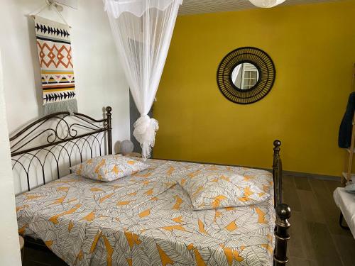 ein Schlafzimmer mit einem Bett mit gelber Wand und einem Spiegel in der Unterkunft Villa Délia in Le Lamentin