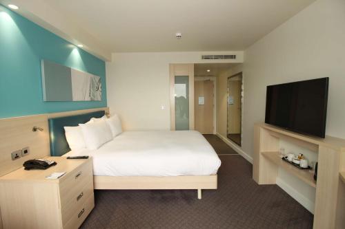a hotel room with a bed and a flat screen tv at Hampton By Hilton London Docklands in London