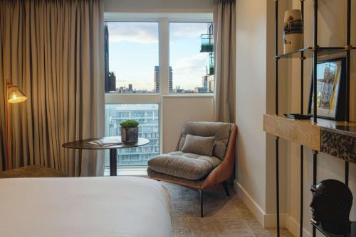um quarto de hotel com uma cama e uma cadeira e uma janela em Lincoln Plaza Hotel London, Curio Collection By Hilton em Londres