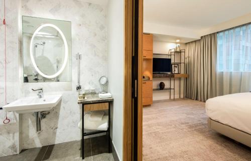 baño con lavabo, cama y espejo en Lincoln Plaza Hotel London, Curio Collection By Hilton, en Londres