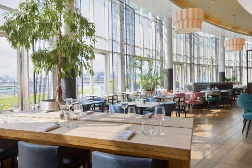 um restaurante com mesas e cadeiras e janelas grandes em DoubleTree By Hilton London Excel em Londres