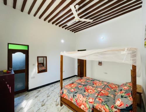 1 dormitorio con 1 cama y ventilador de techo en Happy House Nungwi en Nungwi