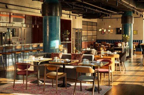 a restaurant with tables and chairs in a room at The Gantry London, Curio Collection By Hilton in London