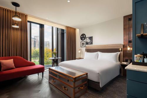 Habitación de hotel con cama y silla roja en The Gantry London, Curio Collection By Hilton en Londres