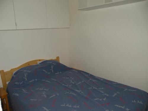 a bed with a blue comforter with writing on it at Au Coeur De La Station in Les Deux Alpes