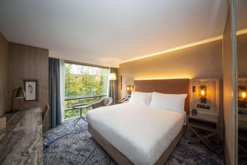 キングストン・アポン・テムズにあるダブルツリー バイ ヒルトン ロンドン キングストン アポン テムズの大きなベッドと窓が備わるホテルルームです。