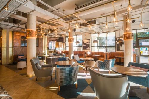 un restaurante con mesas, sillas y ventanas en DoubleTree by Hilton London Kingston Upon Thames en Kingston upon Thames