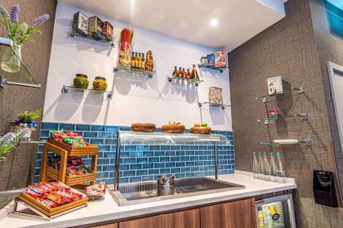a kitchen with a sink and a blue tiled wall at DoubleTree by Hilton London Angel Kings Cross in London