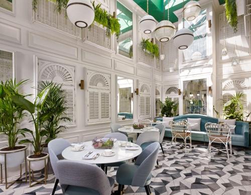 une salle à manger avec des tables, des chaises et des plantes dans l'établissement 100 Queen’s Gate Hotel London, Curio Collection by Hilton, à Londres