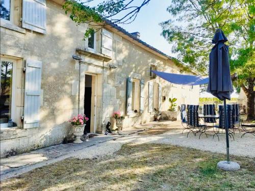 un parasol et des chaises devant une maison dans l'établissement Le Cœur du Breuil, à Segonzac