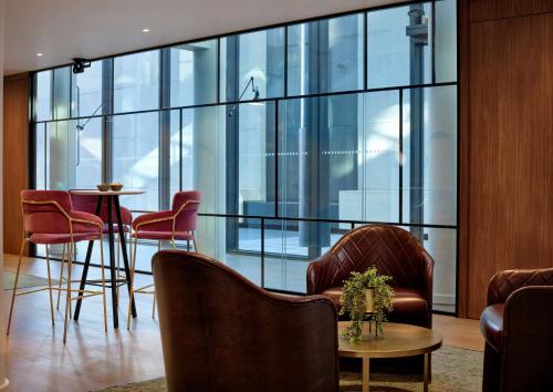 a lobby with chairs and a table and windows at The Westminster London, Curio Collection by Hilton in London