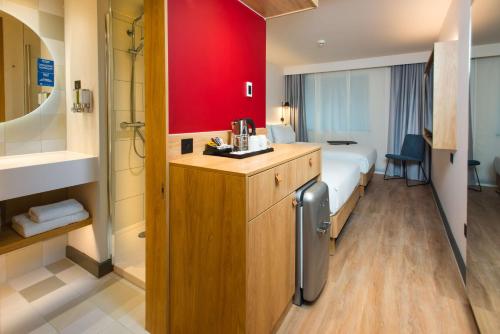 una camera d'albergo con letto e parete rossa di Hampton by Hilton London Park Royal a Londra