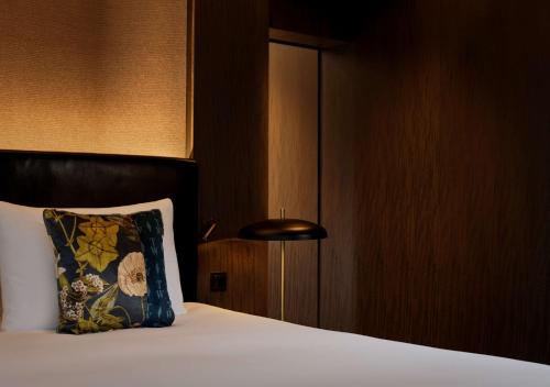 a bedroom with a bed with a pillow and a lamp at The Westminster London, Curio Collection by Hilton in London