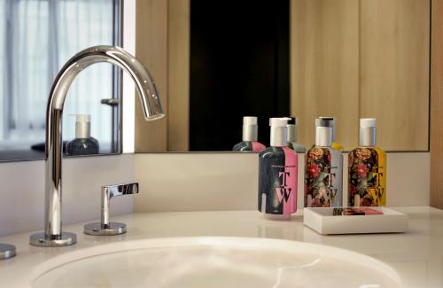 a bathroom counter with a sink with three bottles of soap at The Westminster London, Curio Collection by Hilton in London