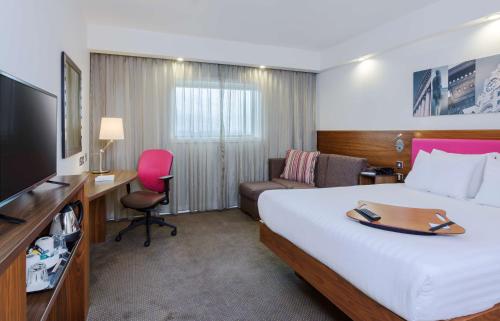 Habitación de hotel con cama grande y TV en Hampton by Hilton Liverpool John Lennon Airport en Speke