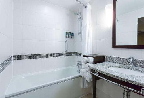 Baño blanco con lavabo y bañera en Hampton by Hilton Liverpool John Lennon Airport en Speke