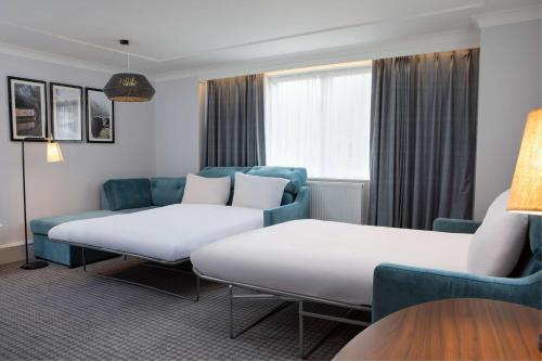 a hotel room with two beds and a couch at DoubleTree by Hilton Stoke-on-Trent, United Kingdom in Stoke on Trent