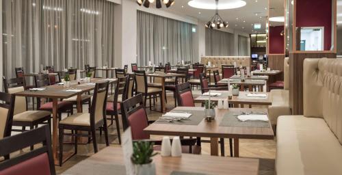 une salle à manger avec des tables et des chaises en bois dans l'établissement Hilton Garden Inn Manchester Emirates Old Trafford, à Manchester