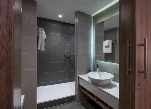 a bathroom with a shower and a sink and a tub at Hilton Garden Inn Manchester Emirates Old Trafford in Manchester