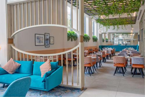 a restaurant with blue couches and tables and chairs at Hilton Garden Inn Stoke On Trent in Stoke on Trent