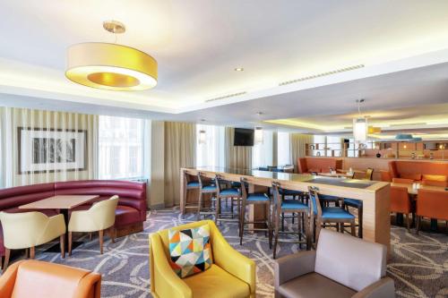 un restaurante con mesas y sillas y un bar en Hampton by Hilton Newcastle, en Newcastle