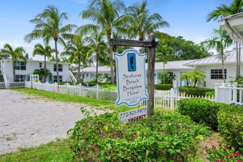 a sign in front of a building with palm trees at Seahorse Beach Bungalows in Fort Pierce
