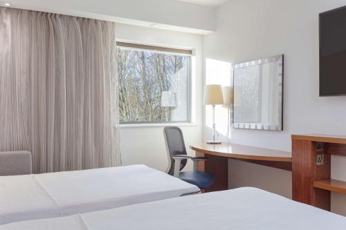 コービーにあるHampton by Hilton Corbyのベッド2台、デスク、窓が備わるホテルルームです。