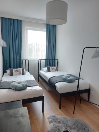um quarto com 2 camas e uma janela com cortinas azuis em La Casa em Piotrków Trybunalski