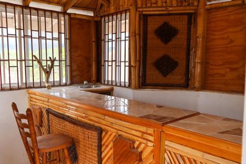 a kitchen with a large wooden counter with chairs and windows at Kokojo Villa in Black River