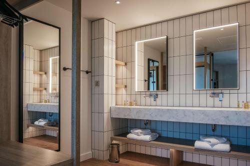 a bathroom with two sinks and two mirrors at Hilton Garden Inn Snowdonia in Conwy