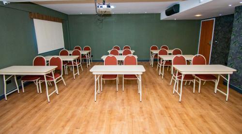 a classroom with tables and chairs in a room with green walls at H+ Hotel in Dourados