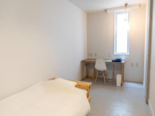 松江的住宿－煎 SEN，一间卧室配有一张床、一张书桌和一个窗户。