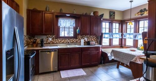 a kitchen with wooden cabinets and a table and a refrigerator at Home Inn The Heart of the Finger Lakes in Geneseo