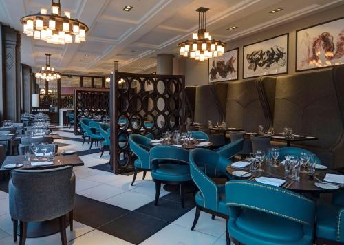 ein Restaurant mit blauen Stühlen, Tischen und Kronleuchtern in der Unterkunft Doubletree by Hilton Edinburgh City Centre in Edinburgh
