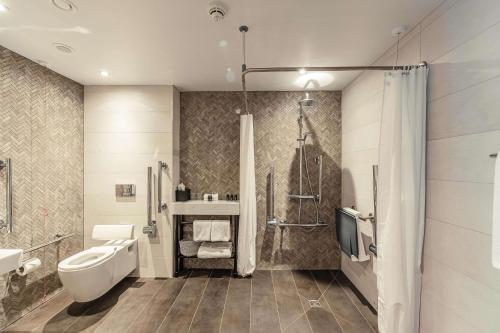a bathroom with a toilet and a sink and a shower at The Fellows House Cambridge, Curio Collection By Hilton in Cambridge