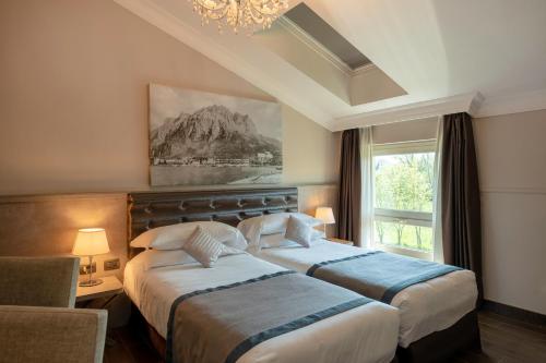 MeroneにあるHotel Il Corazziereのベッド2台と窓が備わるホテルルームです。