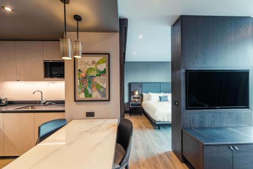 a kitchen and a living room with a table and a television at The Fellows House Cambridge, Curio Collection By Hilton in Cambridge