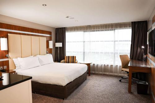 um quarto de hotel com uma cama, uma secretária e uma janela em DoubleTree By Hilton Milton Keynes em Milton Keynes
