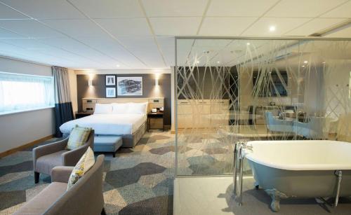 ein Hotelzimmer mit einem Bett und einer Badewanne in der Unterkunft DoubleTree by Hilton Coventry Building Society Arena in Coventry