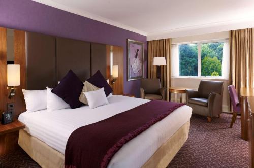 Cette chambre comprend un grand lit et une fenêtre. dans l'établissement DoubleTree by Hilton Sheffield Park, à Sheffield