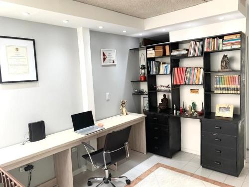 Habitación con escritorio, ordenador portátil y estante para libros. en Hab Nawi con Aire Acondicionado, en Cali