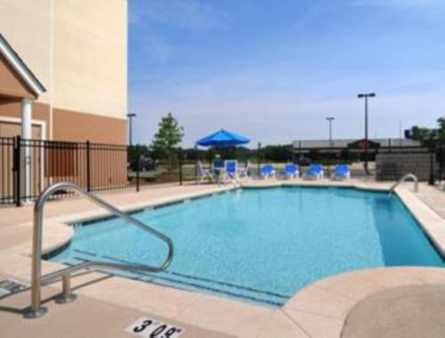 a large swimming pool with chairs and umbrellas at Microtel by Wyndham Perry National Fairground Area I-75 in Perry