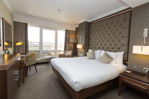 a hotel room with a large bed and a desk at DoubleTree by Hilton London Victoria in London