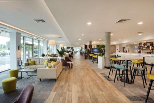 a lobby with couches and chairs and a bar at Hampton By Hilton London Stansted Airport in Stansted Mountfitchet