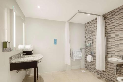 a bathroom with a sink and a shower at Hampton By Hilton London Stansted Airport in Stansted Mountfitchet