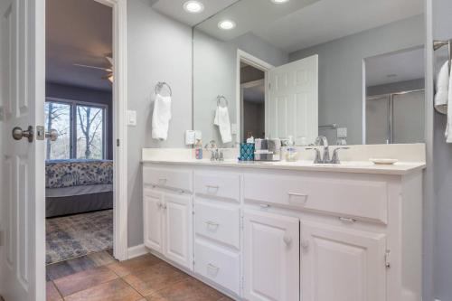 ein weißes Badezimmer mit Waschbecken und Spiegel in der Unterkunft Golfers Getaway in Hot Springs Village