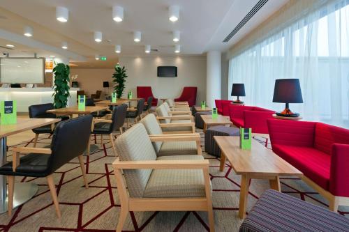 uma sala de espera com mesas e cadeiras vermelhas em Hampton by Hilton London Gatwick Airport em Horley