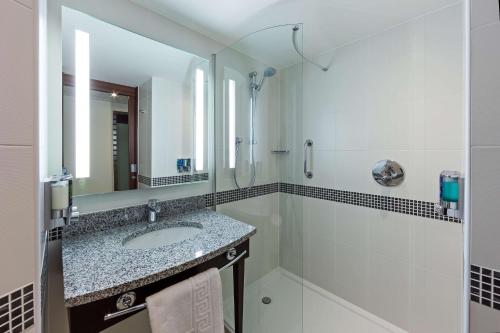 a bathroom with a sink and a shower and a mirror at Hampton by Hilton London Gatwick Airport in Horley